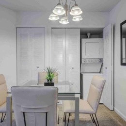 Our apartment community offers in-unit laundry, so you can ditch the trek to the laundromat. Enjoy the ability to tackle your to-do list on your own schedule! dining area with a table and chairs and a laundry closet in the background
